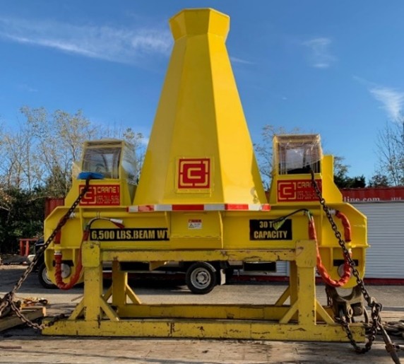 Large yellow industrial lifting beam marked "6,500 lbs. beam wt" and "30 ton capacity," secured with chains, outdoors with trees in the background.